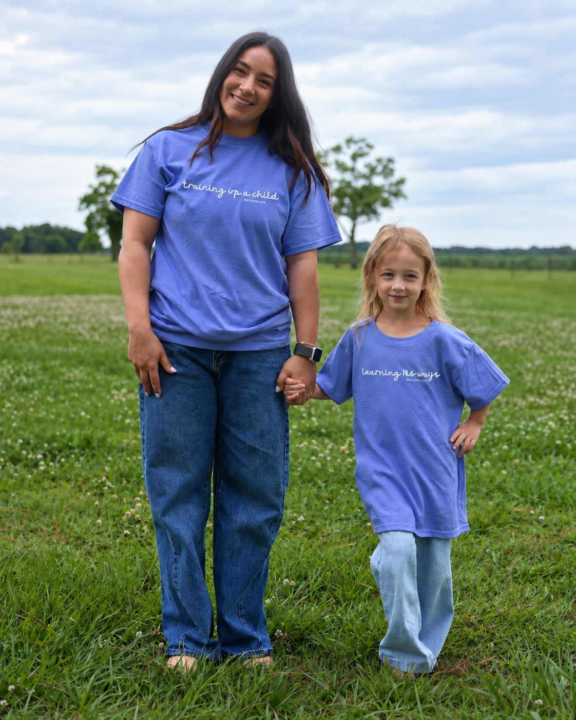 A mother and daughter wearing matching faith-inspired tees in an open field